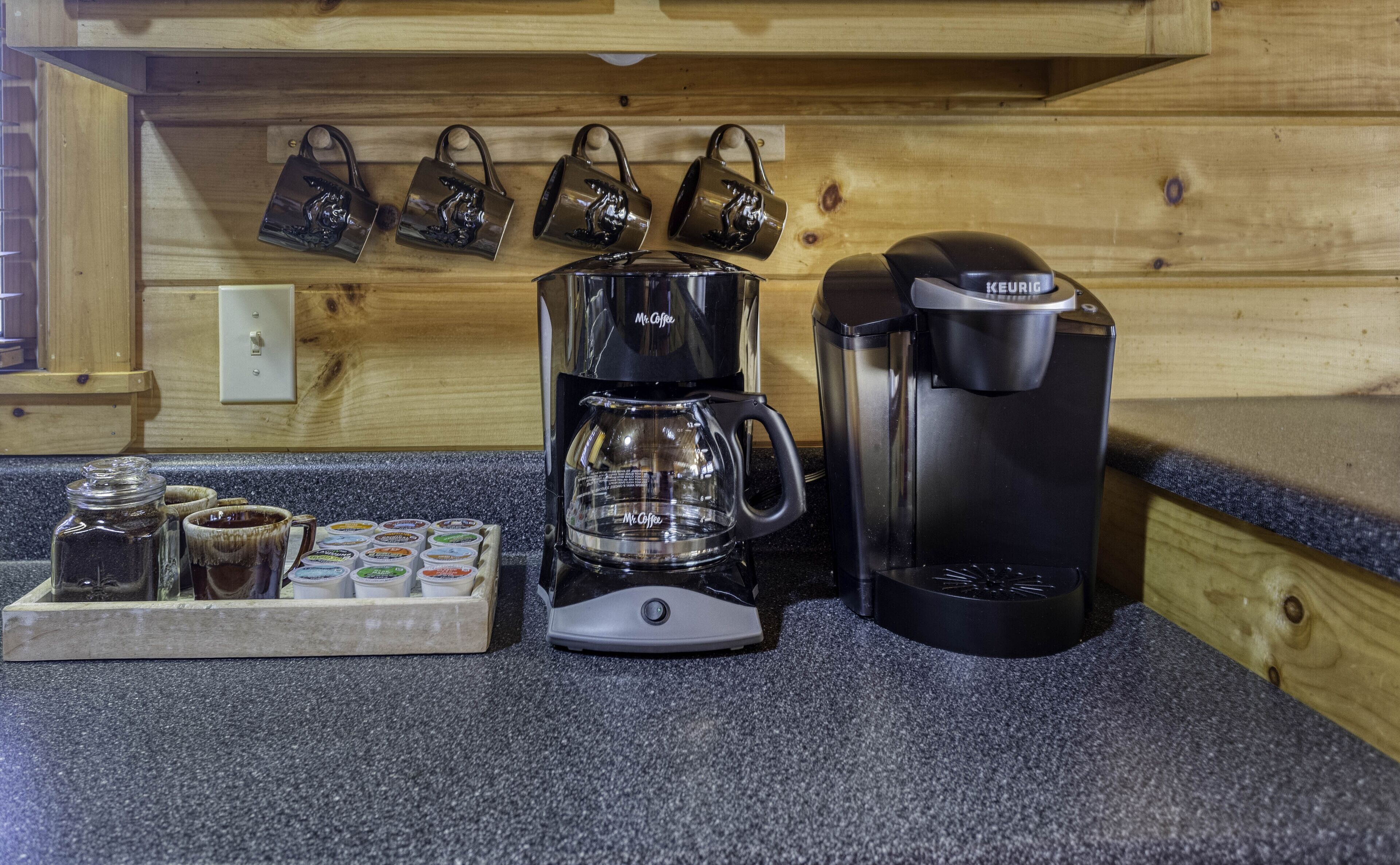 A coffee station with a Mr. Coffee maker, a Keurig, and a tray of coffee pods.