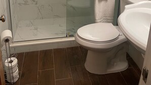 Un baño con ducha de vidrio, inodoro y lavamanos.