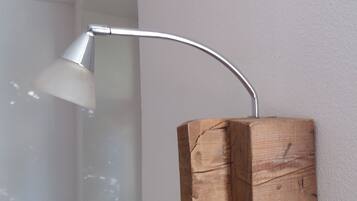 Une pièce moderne avec un mur blanc, une étagère en bois et une lampe de bureau blanche.