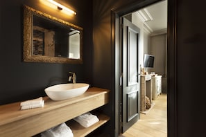 Un baño moderno con un espejo grande, un lavamanos blanco y estantes de madera.