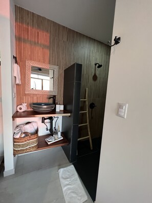 A modern bathroom with a wooden vanity, a mirror, a towel rack, and a towel on the floor. - Villa Vega @ Mangata (Quepos)