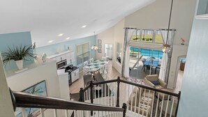 A spacious living area with a dining table, kitchen, and a view of a pool. - 6 BR, 5 BA, Close to Disney, Salt Water Pool, Games Room, POOL HEAT INCLUDED ! (Kissimmee)