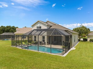 A house with a covered pool area, a large lawn, and a neighboring swimming pool. - 6 BR, 5 BA, Close to Disney, Salt Water Pool, Games Room, POOL HEAT INCLUDED ! (Kissimmee)
