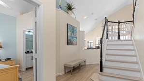 A spacious living area with a wooden staircase, a bench, and a painting of a beach scene. - 6 BR, 5 BA, Close to Disney, Salt Water Pool, Games Room, POOL HEAT INCLUDED ! (Kissimmee)