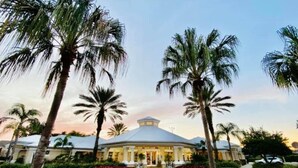 A hotel with a central dome structure, surrounded by palm trees and a well-maintained lawn. - 6 BR, 5 BA, Close to Disney, Salt Water Pool, Games Room, POOL HEAT INCLUDED ! (Kissimmee)