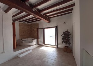 Ein geräumiges Zimmer mit Steinwand, Badewanne und einer Topfpflanze.