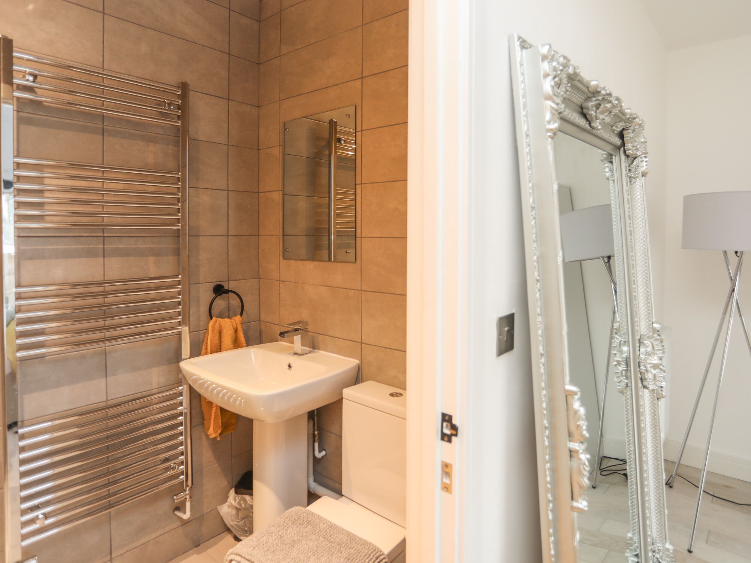 A modern bathroom with a large mirror, a sink, and a towel rack.