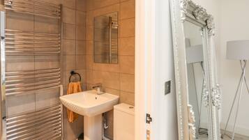 A modern bathroom with a large mirror, a sink, and a towel rack.