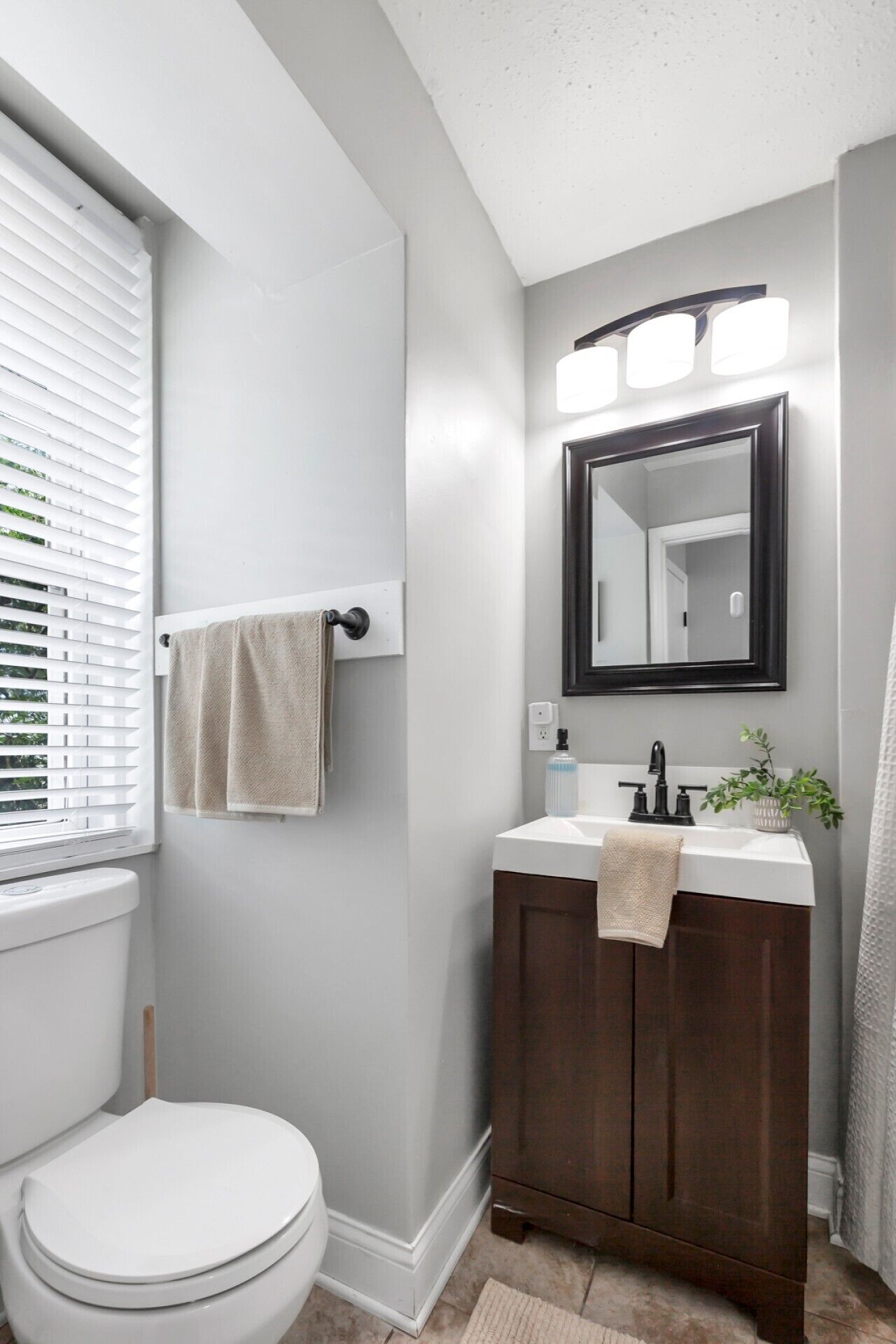 Un bagno con il water, un lavandino con uno specchio sopra e un asciugamano appeso al muro.