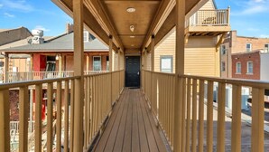 A wooden deck with a railing, leading to a building entrance. - The Loft on Main | Steps to Dining & Nightlife (Saint Charles)