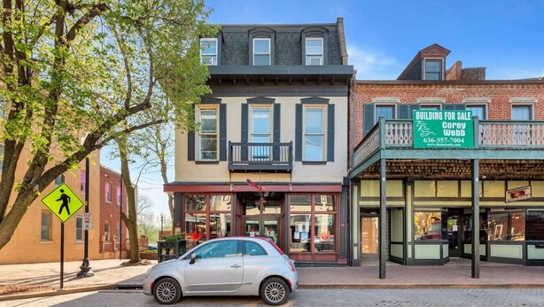 A building for sale with a storefront, a car parked in front, and a pedestrian crossing sign. - The Loft on Main | Steps to Dining & Nightlife (Saint Charles)