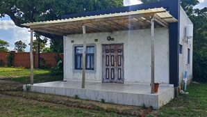 A small, single-story building with a covered porch, a door, and a window. - Self-contained bed sitter overlooking a beautiful scenery in an animal farm. (Lilongwe)