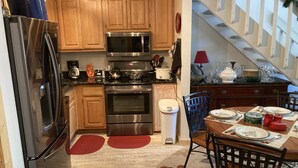 Une cuisine avec des meubles en bois, des appareils électroménagers en acier inoxydable, une table à manger avec des chaises et un escalier.