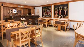 Un restaurante con mobiliario de madera, una zona de bar y elementos decorativos en la pared.