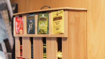 Une vitrine en bois contenant des sachets de thé étiquetés « Twinings » et « Thé vert pur ».