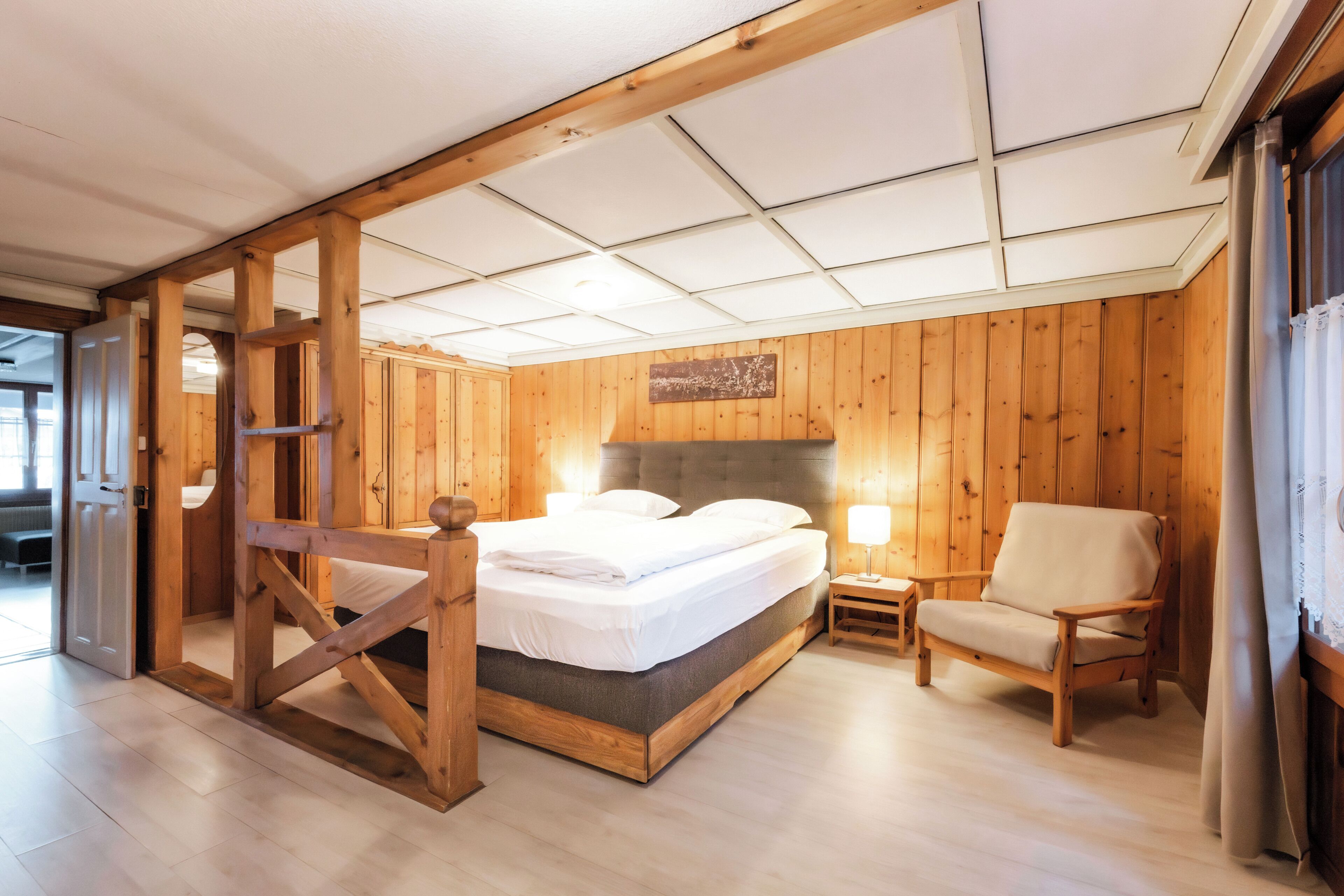 Una habitación con paneles de madera, una cama, una silla y una mesita.