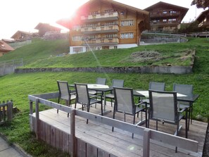 Een terras met zitplaatsen buiten en uitzicht op een gebouw op een heuvel.