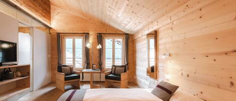A cozy wooden cabin room with a bed, a desk, and a television.