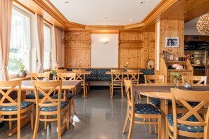 Een houten interieur met tafels, stoelen, een bank en een bar.