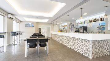 A modern bar area with a checkered tile bar counter, black bar stools, and pendant lighting.