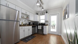 A modern kitchen with white cabinets, stainless steel appliances, and a wooden floor. - 4BR Home, Hot Tub, Near Beach & Wilton Manors (Oakland Park)