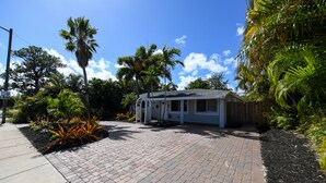 A single-story house with a paved driveway, surrounded by tropical vegetation and a clear blue sky. - 4BR Home, Hot Tub, Near Beach & Wilton Manors (Oakland Park)