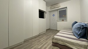 A bedroom with a bed, a wardrobe, a door with a window, and an air conditioning unit. - Capo first floor (Vodice)