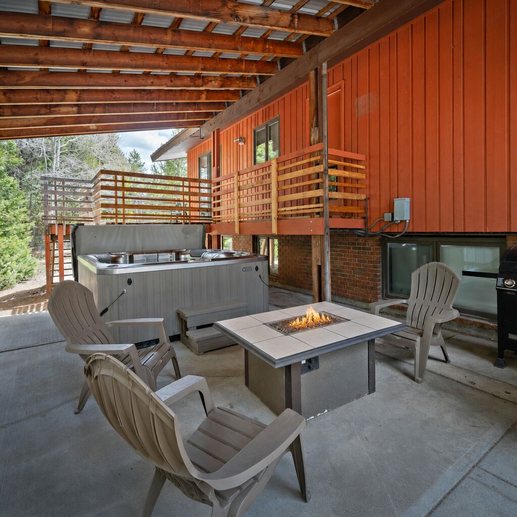 An outdoor patio with a fire pit, seating, and a grill area.