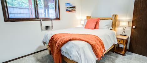 Une chambre à coucher avec un lit, une fenêtre, un tableau et une table de chevet.