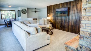 A living room with a sectional sofa, a round coffee table, and a fireplace. - Geyser Getaway (West Yellowstone)