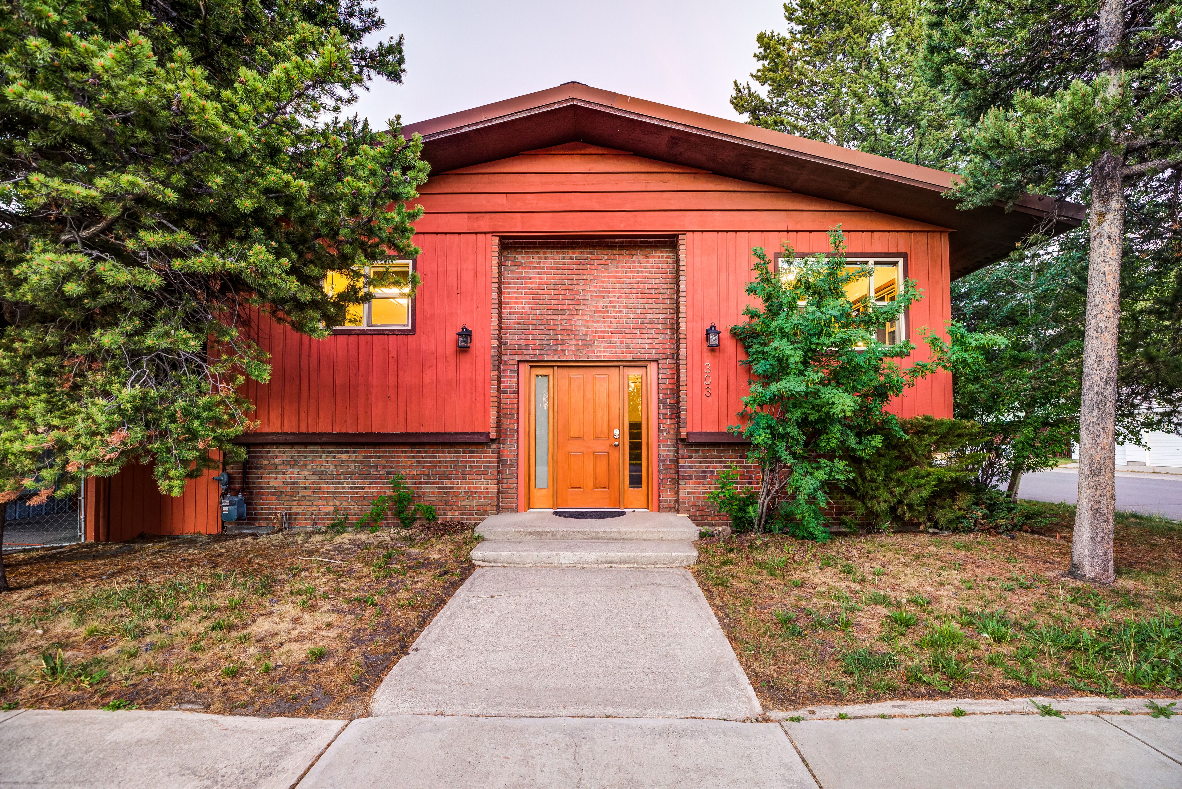 Una casa de ladrillo rojo con puerta principal, un pequeño porche y una entrada para vehículos.