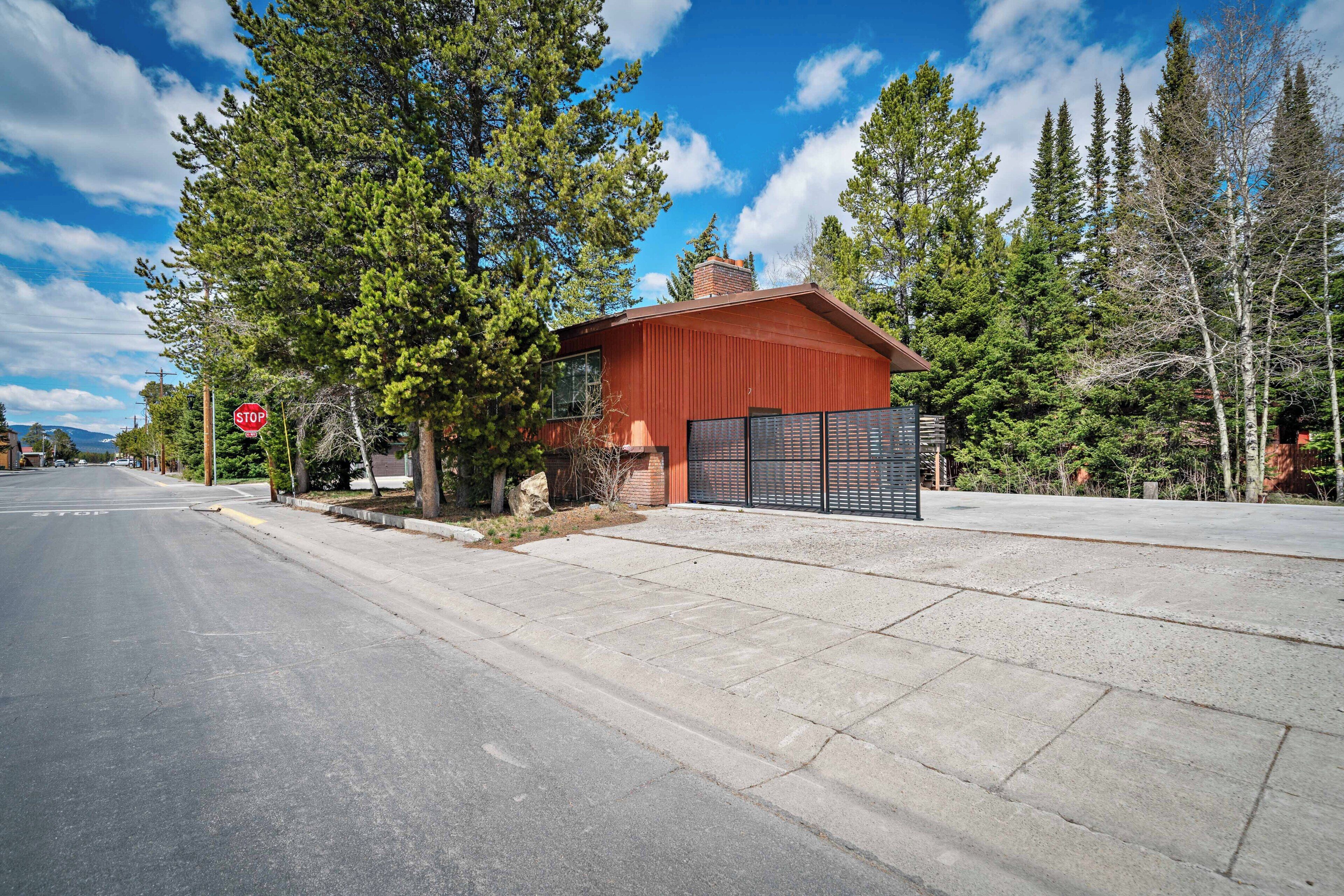 Un bâtiment rouge avec une porte de garage, entouré d’arbres et sous un ciel dégagé.