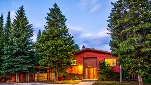 A red building with a brick facade, surrounded by tall evergreen trees. - Geyser Getaway (West Yellowstone)
