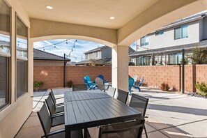 An outdoor patio with a table and chairs, a brick wall, and a covered area with a view of neighboring buildings.