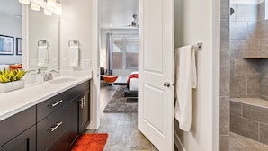 Een moderne badkamer met een dubbele wastafel, een grote spiegel en een douchehoek.