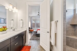 A modern bathroom with a double sink, a large mirror, and a shower area.