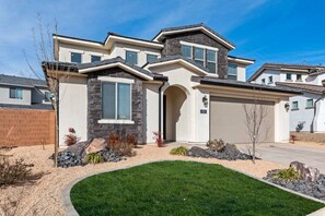 A modern two-story house with a stone facade, a garage, and a well-maintained lawn.