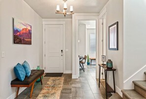 A hallway with a bench, a rug, a painting, and a staircase. - Wanderlust: Luxury 5 BR/ 4 BA Home and Retreat (Washington)