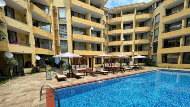 A multi-story hotel with a swimming pool, sun loungers, and umbrellas. - Stylish 1-bed Apartment in Sunny Beach (Sunny Beach)