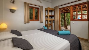 A bedroom with a bed, pillows, a nightstand, a lamp, a window, and a wooden shelf. - your favorite hangout on Bonaire (Kralendijk)