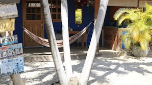 A building with a red-tiled roof, a wooden door, and a hammock in front. There are multiple license plates on a post in front of the building. - your favorite hangout on Bonaire (Kralendijk)