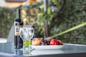 A bottle of wine, two glasses, and a plate of fruit on a table.