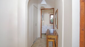 A narrow hallway with a wooden table and a hanging light fixture. - NIKOLOUZOS SUNNY ESTATE (Corfu)