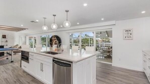 Una cucina moderna con un'isola grande, elettrodomestici in acciaio inossidabile e illuminazione a sospensione.
