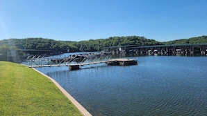 Un lago calmo con un molo e una zona erbosa.