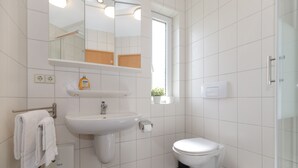 Un baño con lavabo, espejo e inodoro.