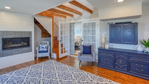 A spacious living room with a fireplace, wooden beams, a staircase, and a blue cabinet. - Nautical Soul, Modern Comfort: Canalfront Park Living in Heart of Historic Lewes (Lewes)