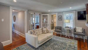 A spacious living room with a white sofa, two armchairs, a patterned rug, and a television on the wall. - Nautical Soul, Modern Comfort: Canalfront Park Living in Heart of Historic Lewes (Lewes)