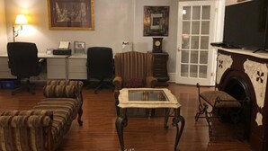 Un salon comprenant un canapé, des fauteuils, une table basse, une cheminée et un téléviseur.