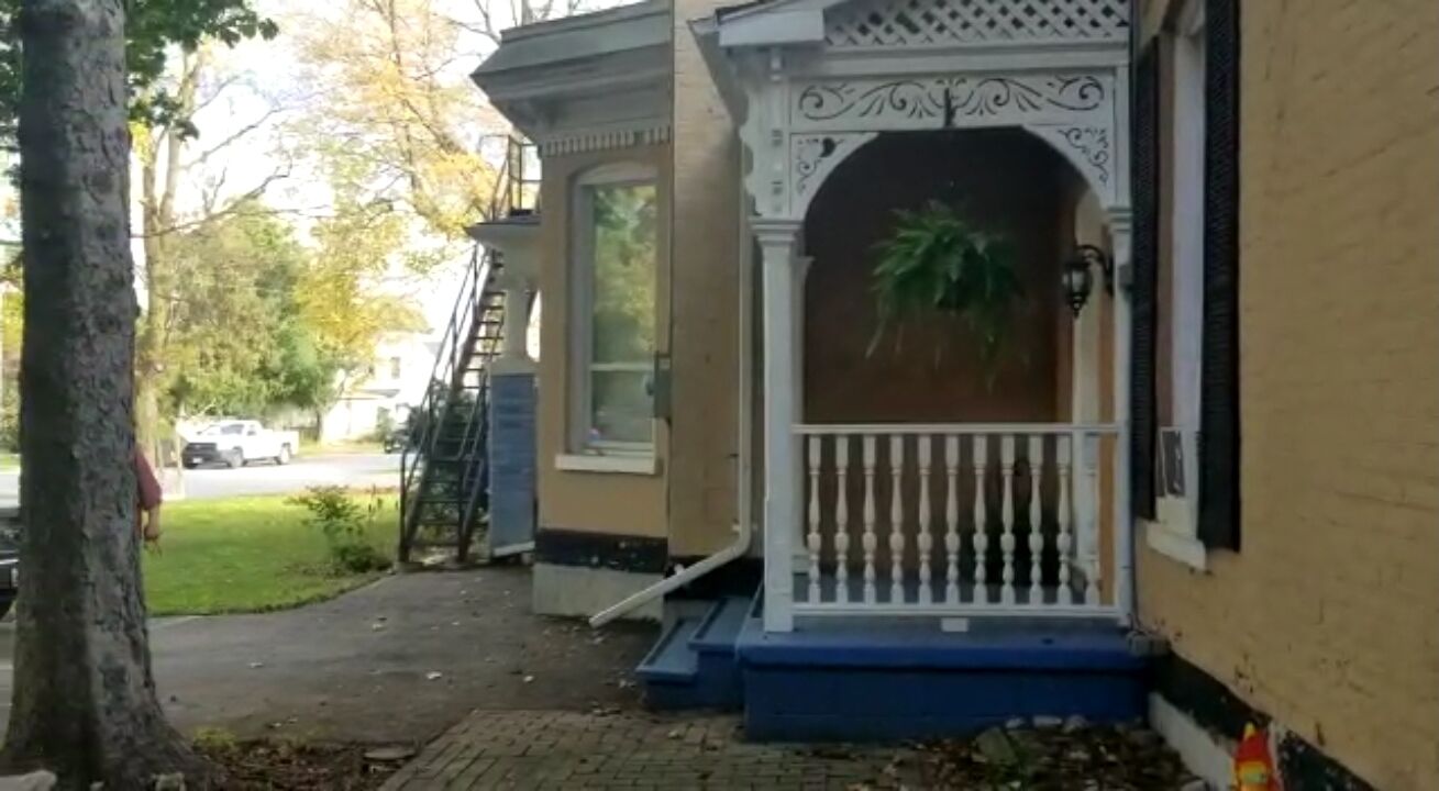 A residential building with a porch, a small staircase, and a garage door.